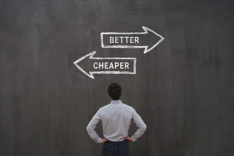 Business owner standing in front of chalkboard arrows showing choice between cheaper and better, symbolizing website investment decisions.
