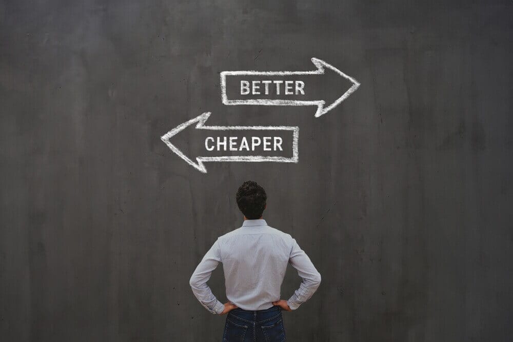 Business owner standing in front of chalkboard arrows showing choice between cheaper and better, symbolizing website investment decisions.