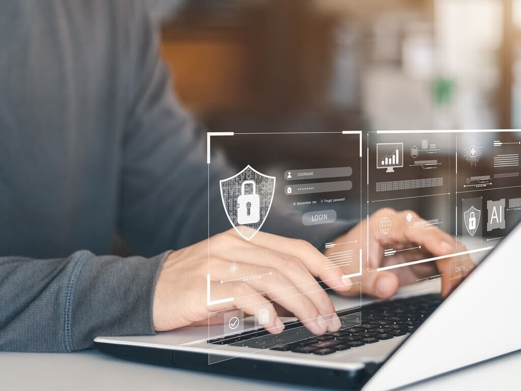 Hands typing on laptop with digital security overlay representing remote IT services.
