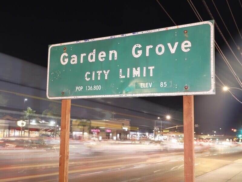 Garden Grove city limit sign at night with blurred traffic in the background. Ideal for highlighting Garden Grove website design services by OC Websites.