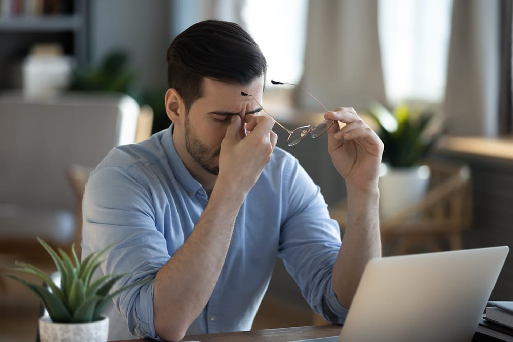 Frustrated small business owner sitting at a desk with a laptop, facing website issues,