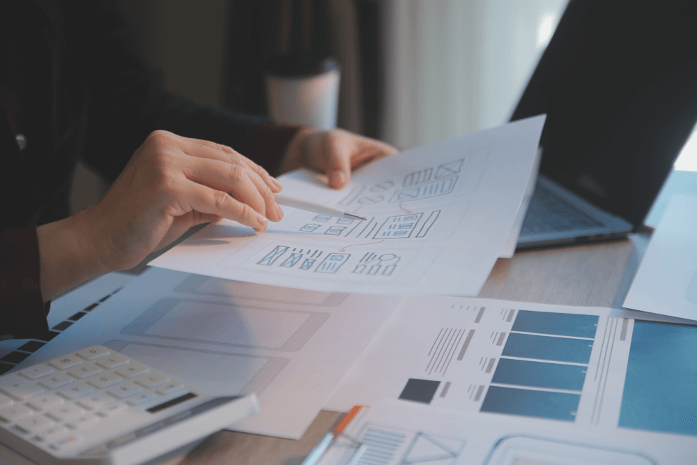 Web designer reviewing printed wireframes and layout plans during the custom website design process.