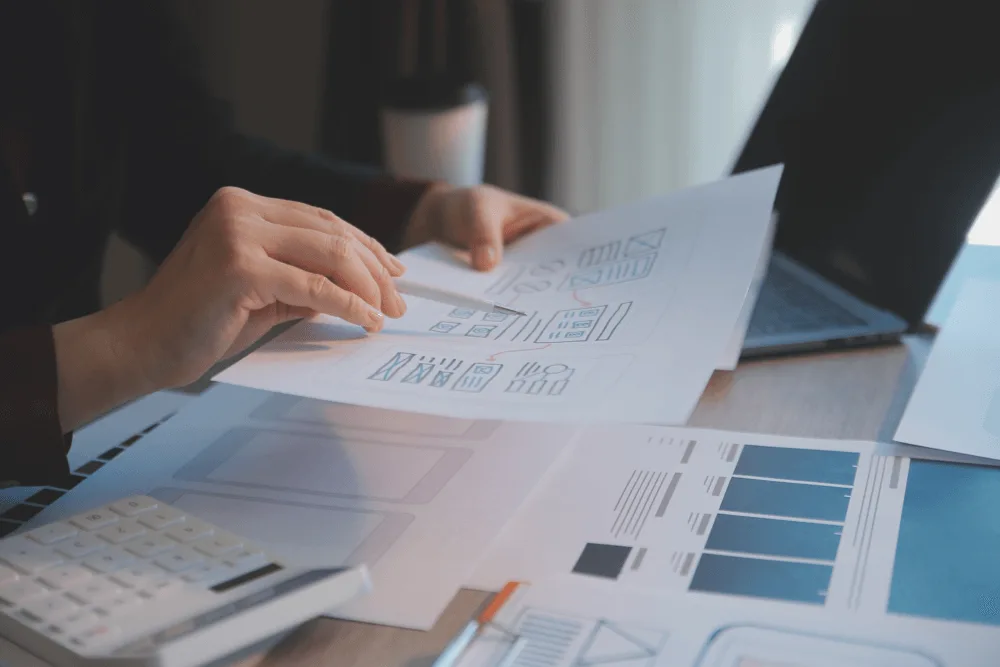 Web designer reviewing printed wireframes and layout plans during the custom website design process.