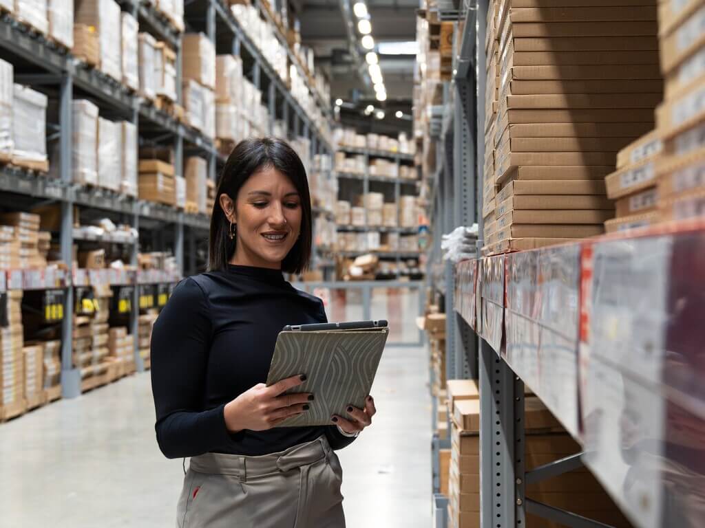 Business owner managing inventory on tablet in warehouse — example of wholesale website design built for real operations.