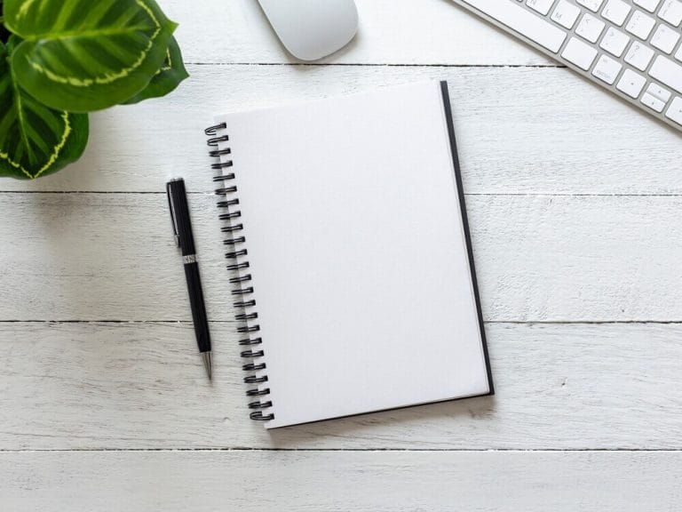 Minimal workspace with notebook and pen, representing clarity and restraint in website content writing.