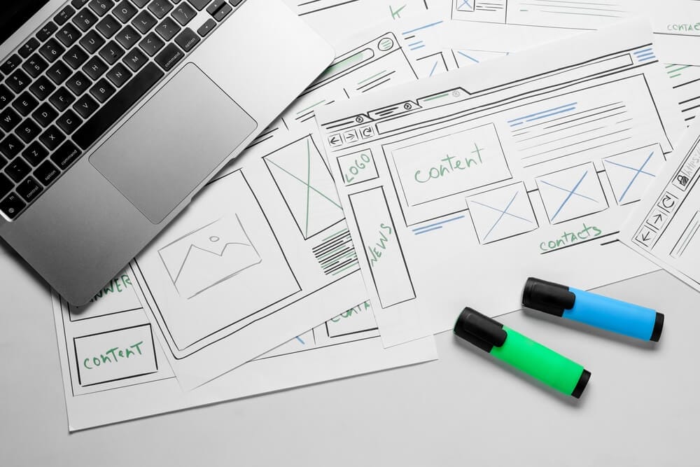 Website planning sketches and laptop representing structured long-term web development.